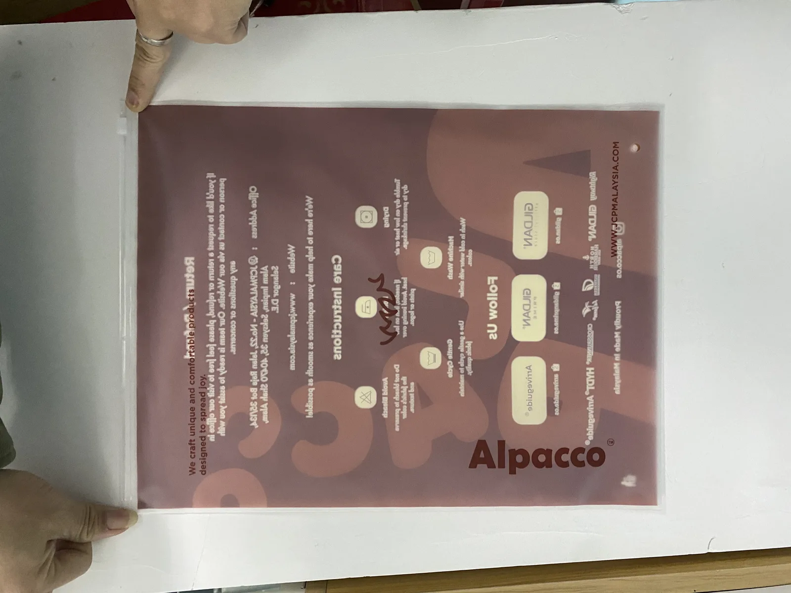 Back of Alpacco tee packaging showing care instructions