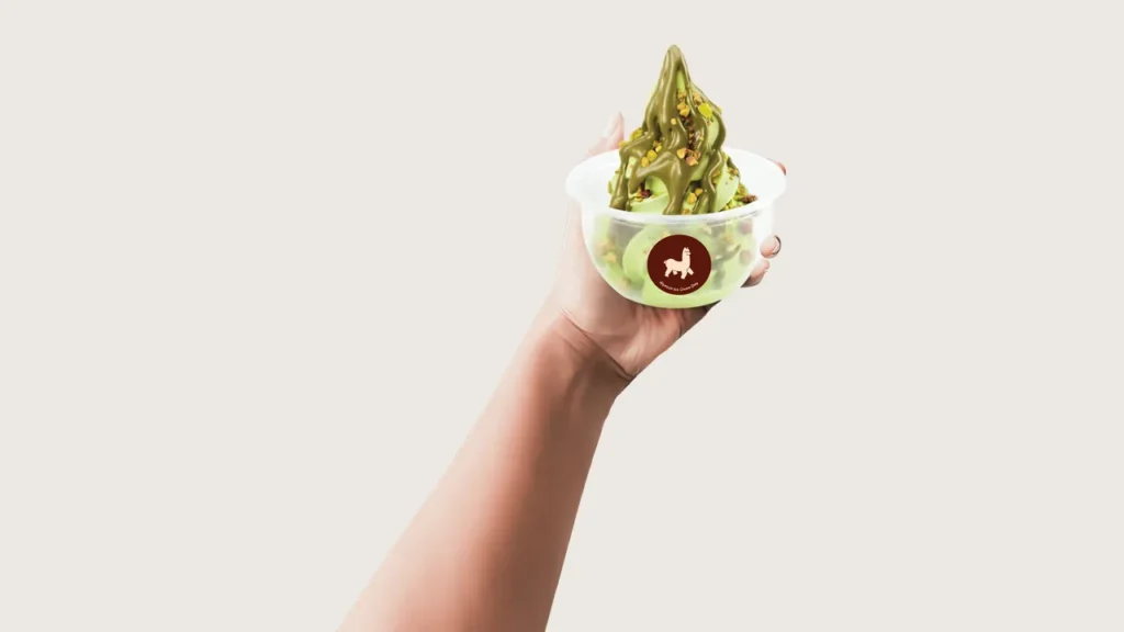 Ice cream photography tips: hand holding up an Alpacco cup of pistachio soft serve